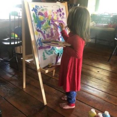 Caroline Estabrook drawing an art holding painting brush and paint.